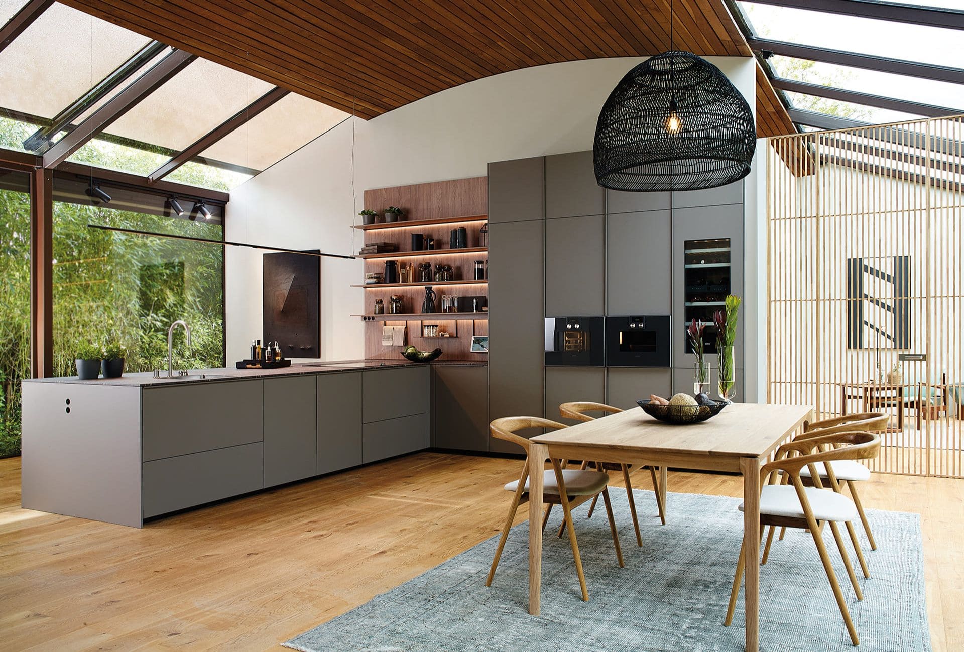 Cocina abierta de diseño moderno en tonos grises con península y estanterías flotantes de madera.